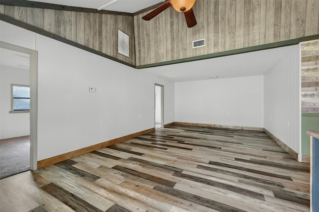 unfurnished room featuring wood walls, ceiling fan, and light hardwood / wood-style flooring