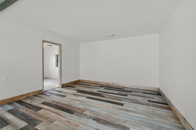 spare room with light hardwood / wood-style floors and wooden walls