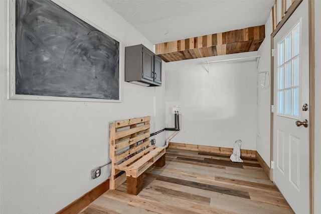 laundry room with a textured ceiling, light hardwood / wood-style flooring, and wood ceiling