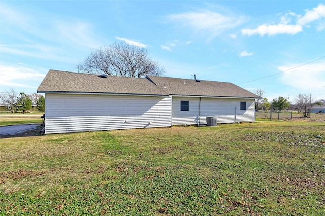 back of house with central air condition unit and a yard