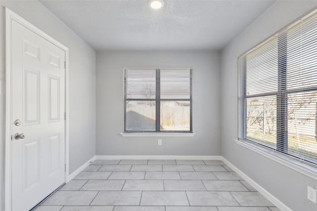 unfurnished room featuring a textured ceiling and light tile patterned flooring