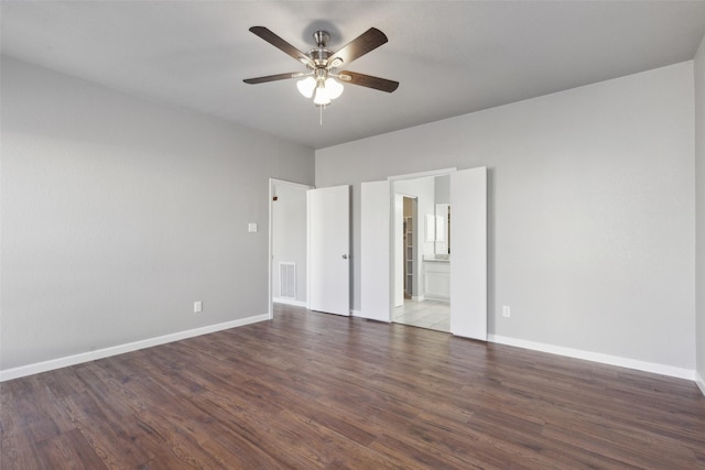 unfurnished bedroom with ceiling fan, dark wood-type flooring, and connected bathroom