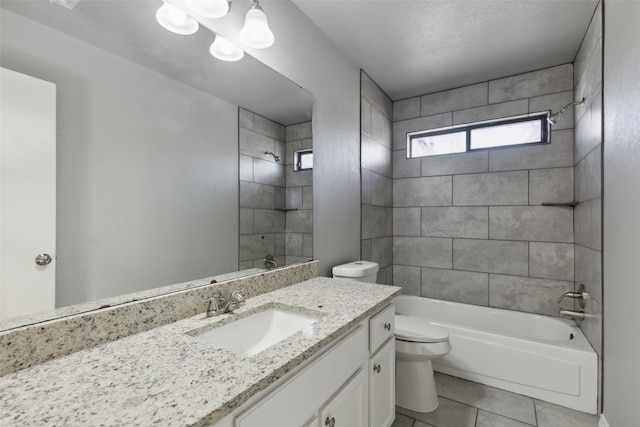 full bathroom featuring a textured ceiling, tiled shower / bath, tile patterned flooring, toilet, and vanity