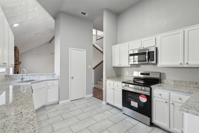 kitchen with sink, stainless steel appliances, white cabinetry, and light stone counters