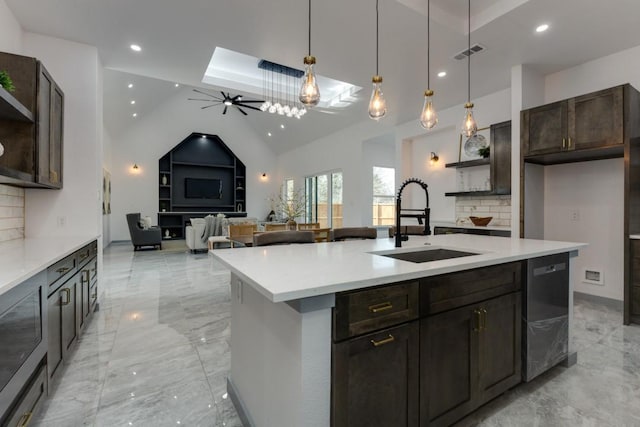 kitchen featuring a center island with sink, ceiling fan, pendant lighting, sink, and tasteful backsplash