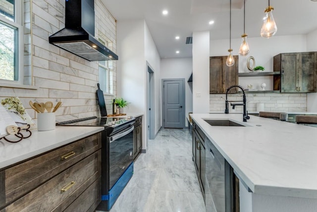 kitchen featuring electric stove, dark brown cabinetry, sink, wall chimney range hood, and decorative light fixtures