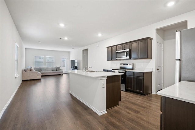 kitchen featuring stainless steel appliances, sink, dark hardwood / wood-style floors, dark brown cabinetry, and a kitchen island with sink