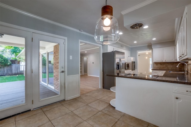 kitchen with stainless steel appliances, sink, white cabinets, ornamental molding, and pendant lighting