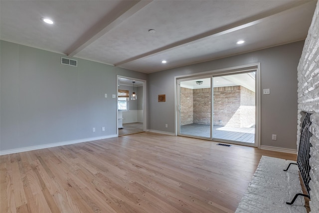 unfurnished living room featuring light hardwood / wood-style flooring, beamed ceiling, and a stone fireplace