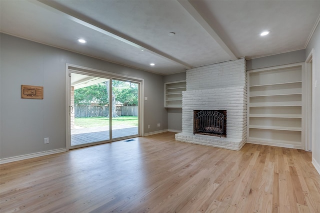 unfurnished living room with light hardwood / wood-style flooring, built in shelves, and a fireplace