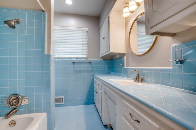 bathroom with tile patterned flooring, vanity, tile walls, and tub / shower combination