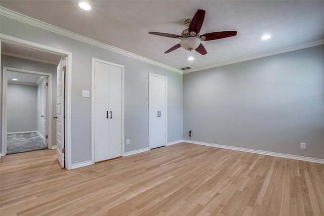 unfurnished bedroom featuring two closets, ceiling fan, light hardwood / wood-style floors, and ornamental molding