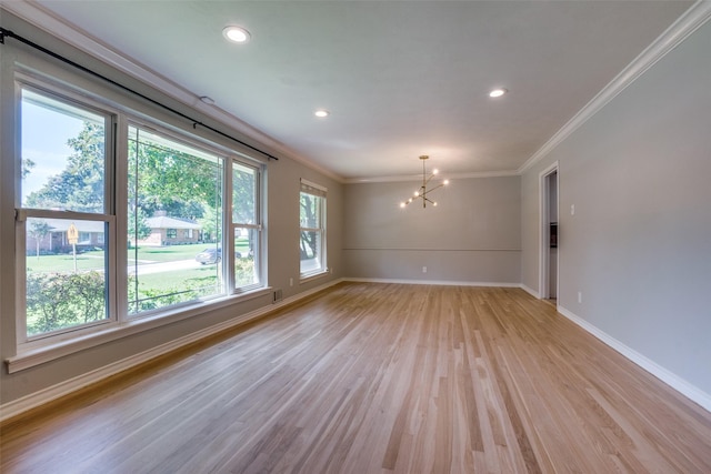 empty room featuring plenty of natural light, crown molding, light hardwood / wood-style floors, and a notable chandelier