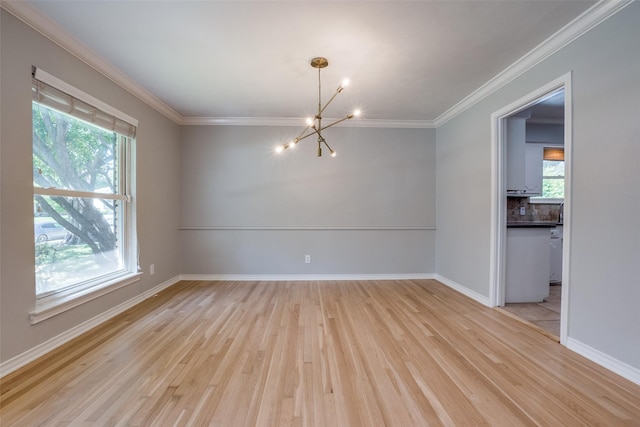 spare room featuring a healthy amount of sunlight, light wood-type flooring, an inviting chandelier, and ornamental molding