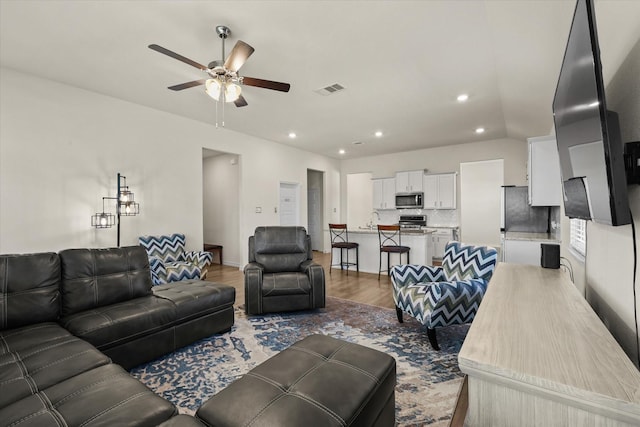 living room featuring ceiling fan, sink, and hardwood / wood-style flooring