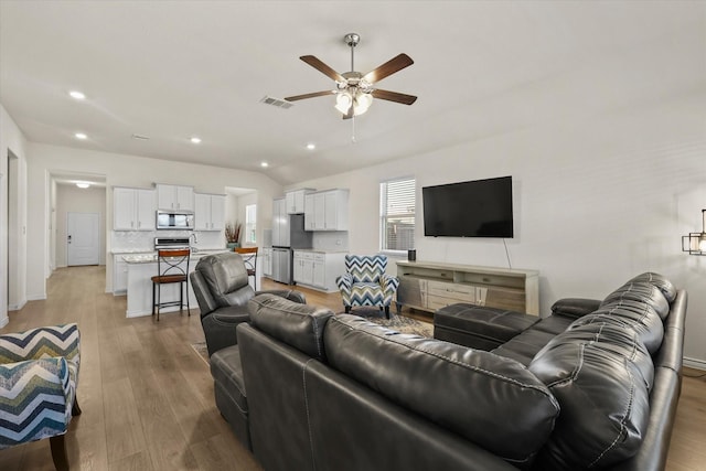 living room with lofted ceiling, light wood-type flooring, and ceiling fan