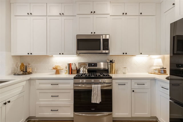 kitchen with stainless steel appliances, white cabinetry, and backsplash