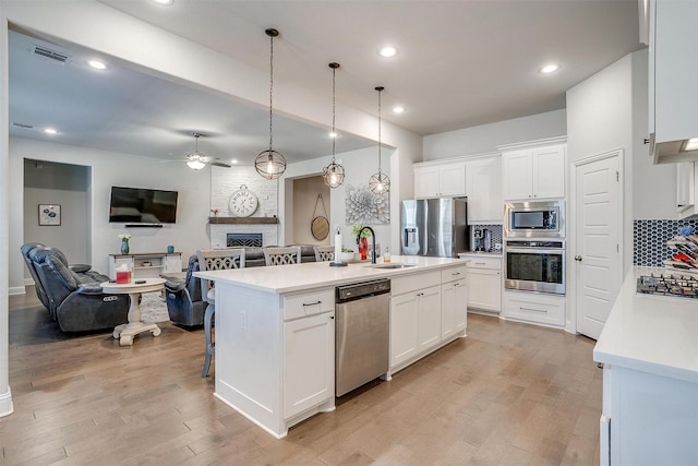 kitchen featuring an island with sink, appliances with stainless steel finishes, backsplash, and white cabinets