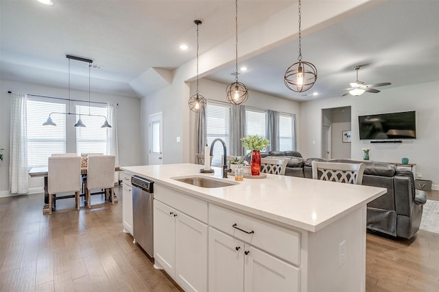 kitchen featuring sink, decorative light fixtures, white cabinetry, and an island with sink