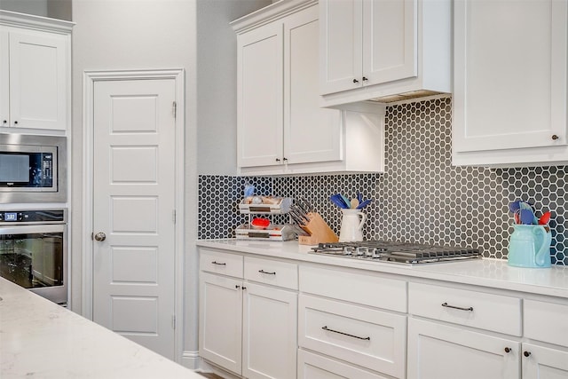 kitchen featuring appliances with stainless steel finishes, white cabinets, and decorative backsplash