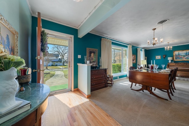 carpeted dining room with beam ceiling, an inviting chandelier, and crown molding