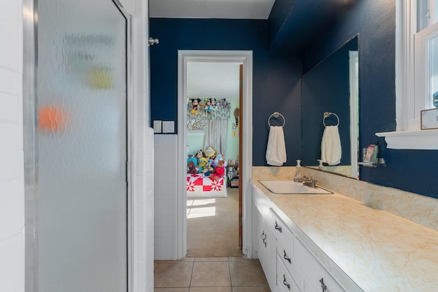 bathroom with a shower with door, vanity, and tile patterned floors