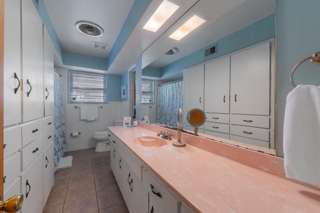 bathroom featuring tile walls, vanity, tile patterned floors, and toilet