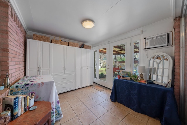 kitchen with white cabinets, french doors, light tile patterned flooring, an AC wall unit, and brick wall