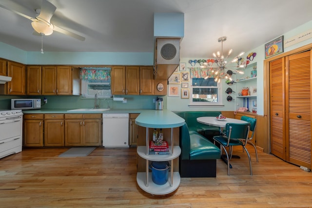 kitchen featuring white appliances, hanging light fixtures, light hardwood / wood-style flooring, and sink