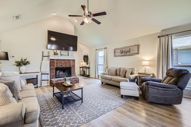 living room featuring ceiling fan, a brick fireplace, a wealth of natural light, and wood-type flooring