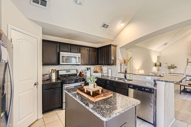 kitchen featuring appliances with stainless steel finishes, a center island, dark stone countertops, and sink