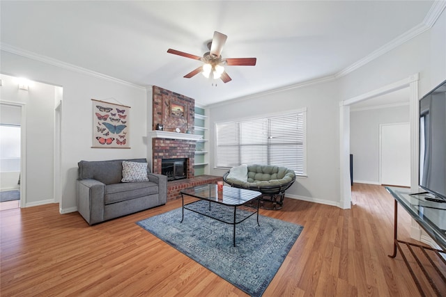 living room with ceiling fan, light hardwood / wood-style floors, built in features, a brick fireplace, and crown molding