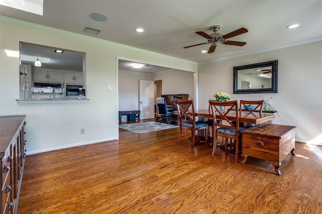 dining area with hardwood / wood-style flooring, crown molding, and ceiling fan