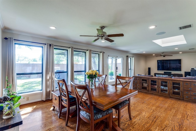 dining area with ornamental molding, a skylight, light hardwood / wood-style floors, and ceiling fan