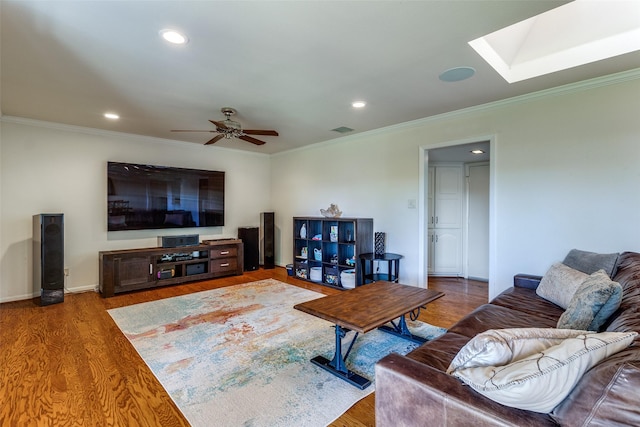 living room featuring ornamental molding, hardwood / wood-style floors, ceiling fan, and a skylight