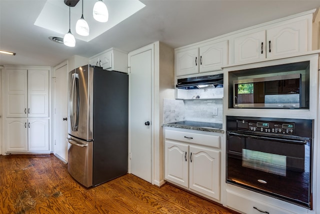 kitchen with stainless steel fridge, black oven, and white cabinets