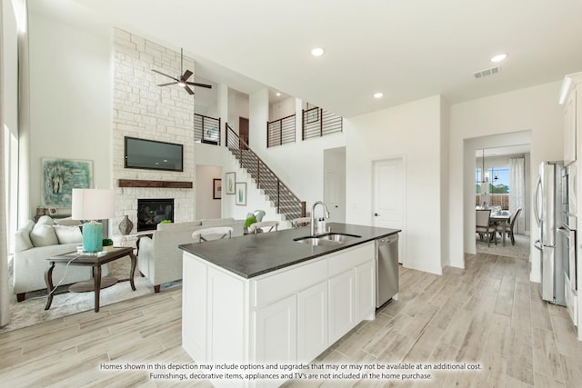 kitchen with appliances with stainless steel finishes, an island with sink, white cabinets, and sink