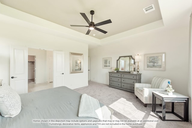 bedroom featuring ceiling fan, light colored carpet, a spacious closet, and a raised ceiling