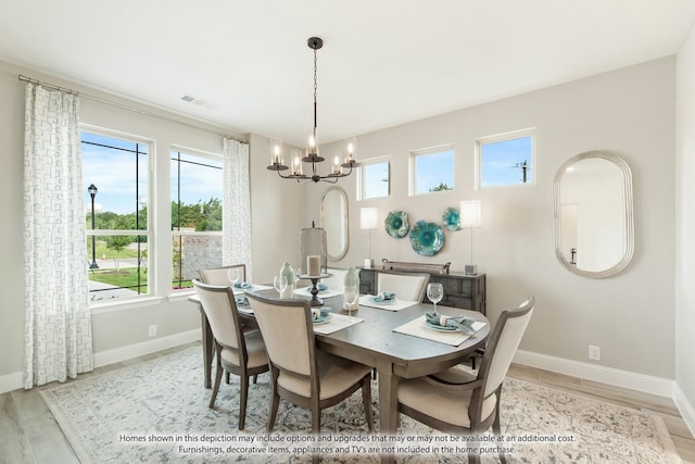 dining room featuring a healthy amount of sunlight, light hardwood / wood-style flooring, and a chandelier