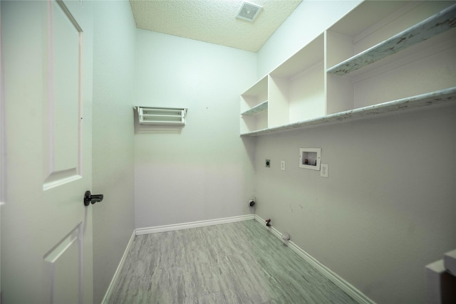 laundry room featuring a textured ceiling, hookup for a washing machine, hookup for an electric dryer, light hardwood / wood-style floors, and hookup for a gas dryer