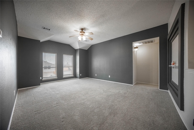 unfurnished room with ceiling fan, vaulted ceiling, a textured ceiling, and carpet flooring