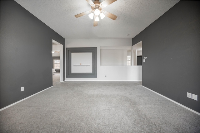 unfurnished room with a textured ceiling, ceiling fan, and carpet