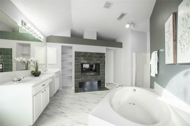 bathroom with a bathtub, vanity, a textured ceiling, and built in shelves