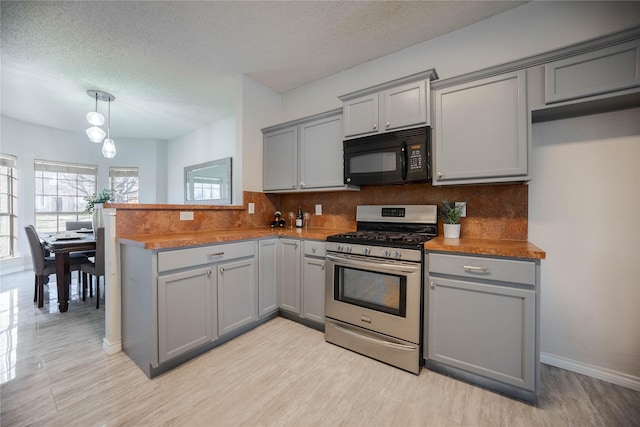 kitchen with gray cabinetry, kitchen peninsula, stainless steel range with gas cooktop, and decorative backsplash