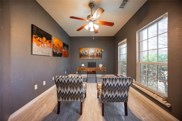 living area featuring a textured ceiling, ceiling fan, and wood-type flooring