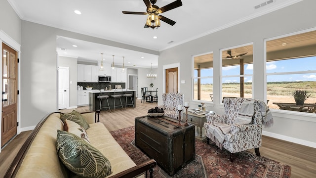 living room featuring ceiling fan, ornamental molding, and hardwood / wood-style flooring