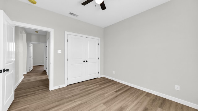 unfurnished bedroom with ceiling fan, wood-type flooring, and a closet