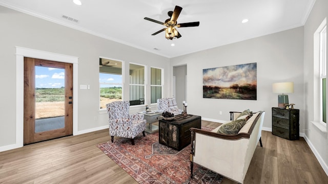 living room with ceiling fan, crown molding, and light wood-type flooring