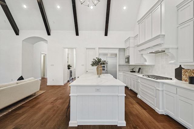 kitchen featuring built in appliances, high vaulted ceiling, a center island, and white cabinets