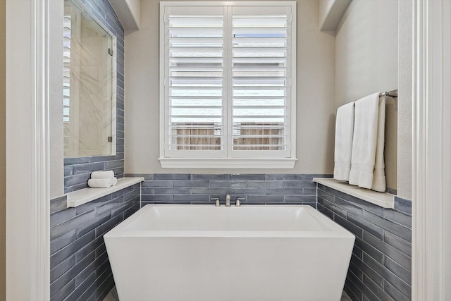 bathroom featuring a washtub and tile walls